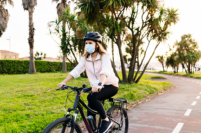 一个戴着口罩的女人骑着自行车。人们为防止COVID-19的传播而戴的口罩也能很好地过滤空气中的花粉和其他过敏原。