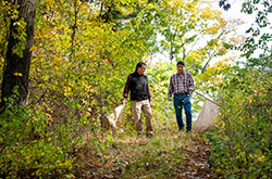 两名男子拖曳白旗虽然森林的灌木丛，拖着蜱虫。TUFTS大学研究人员使其成为2030年通过2030生命莱姆病的目标。