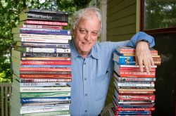 一个男人站在两堆书上几乎和他一样高的书，所有人都被他写着或编辑。