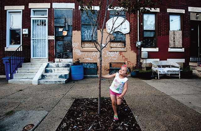 2014年8月14日，卡姆登一座废弃建筑前，一个女孩在一棵死树旁跳舞。“遗弃者”在城市里随处可见。